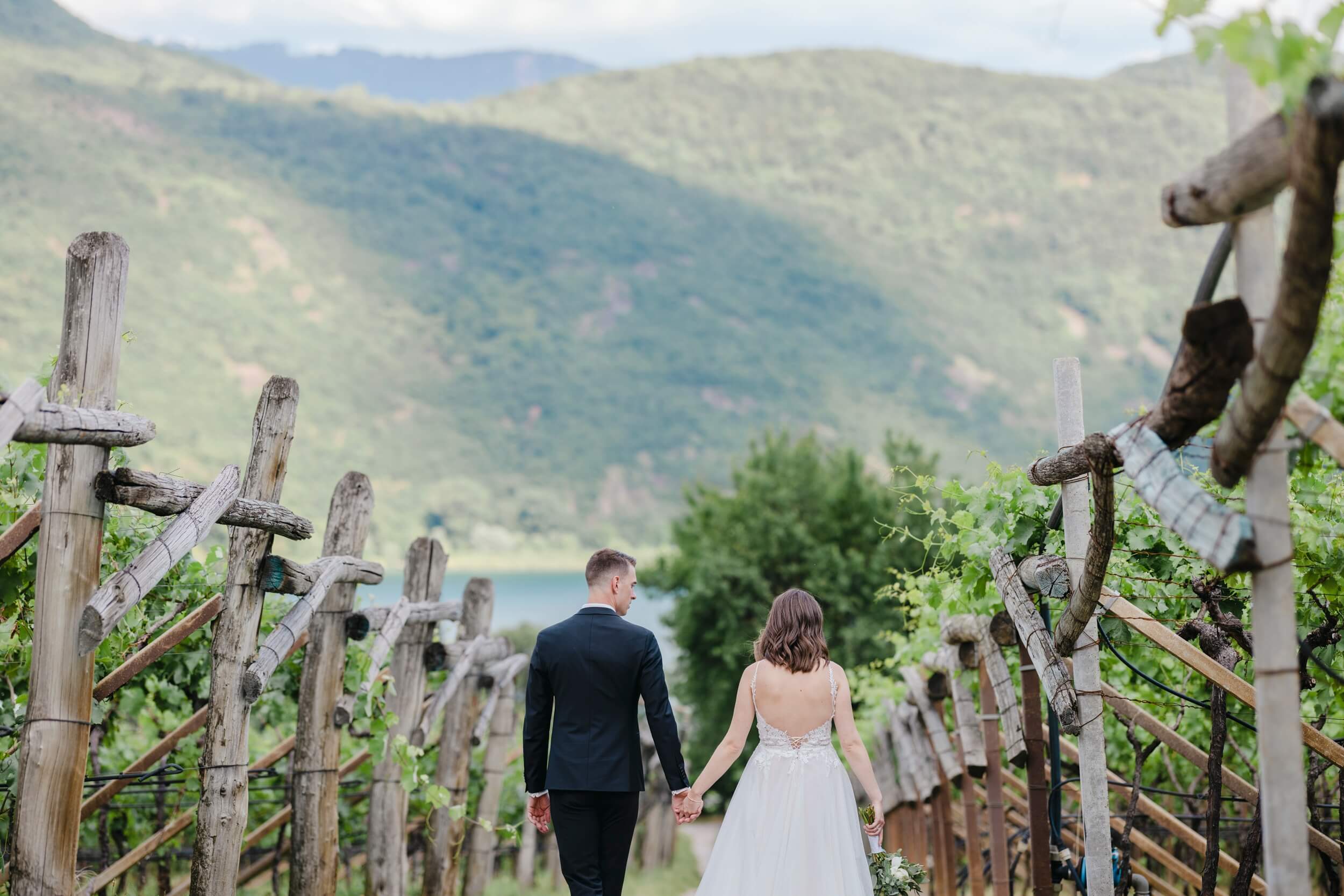 Freie Trauung im Ausland | Hochzeitspaar in den Bergen laufen durch ein Weingut