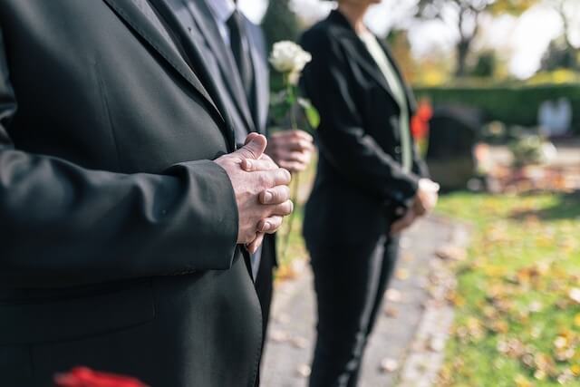 Trauerredner | Trauergäste mit Blumen vor dem Grab