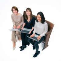 Nadine, Tanja und Yesim sitzen mit Laptops auf einer Bank