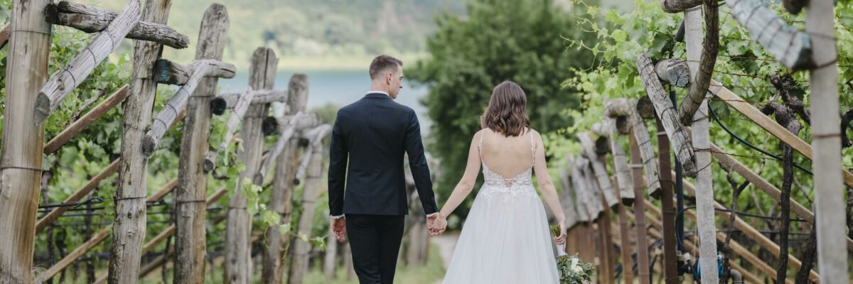 Brautpaar geht Hand-in-Hand durch einen Weinberg