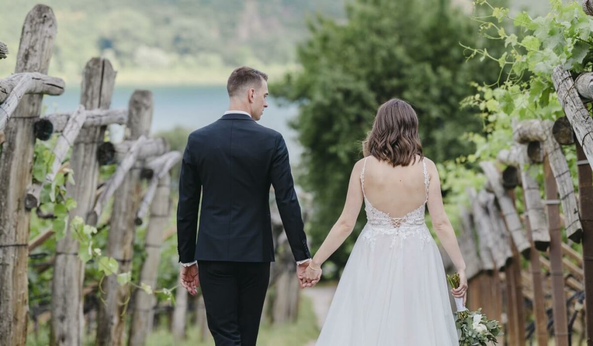Brautpaar geht Hand-in-Hand durch einen Weinberg