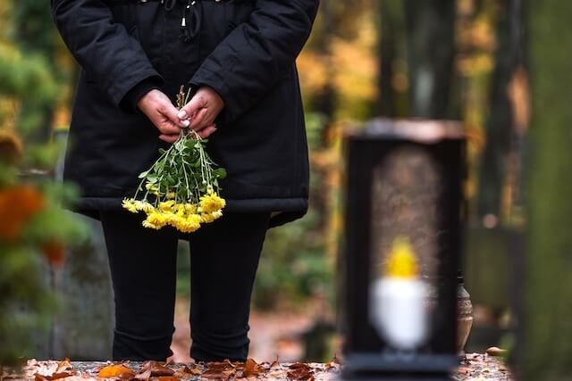 Trauerredner | Trauergast mit Gelben Blumen an einer Grabstätte