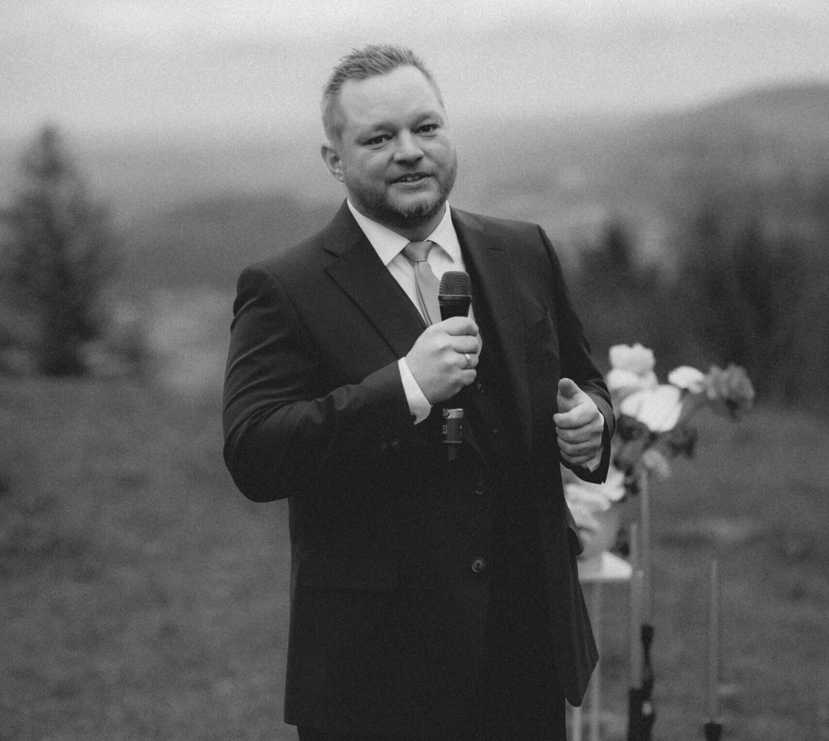 Freier Redner Tom Salzlechner mit Mikro in der Hand bei einer Zeremonie - schwarz weiß Bild