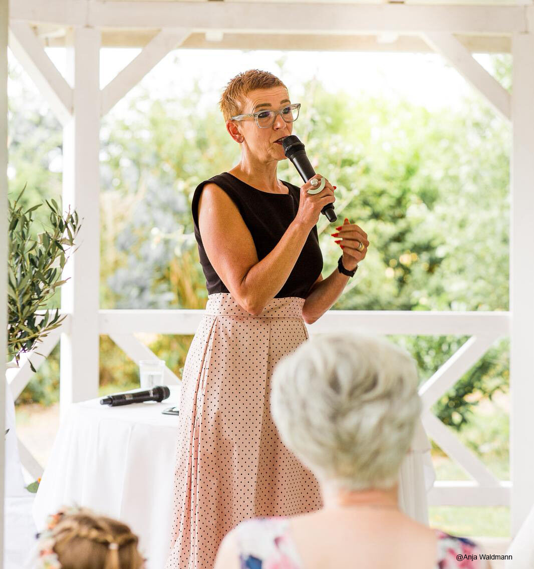 Hier sieht man unsere Freie Rednerin Bettina Manuela Hambuch bei einer Freien Trauung mit einem Mikrofon in der Hand