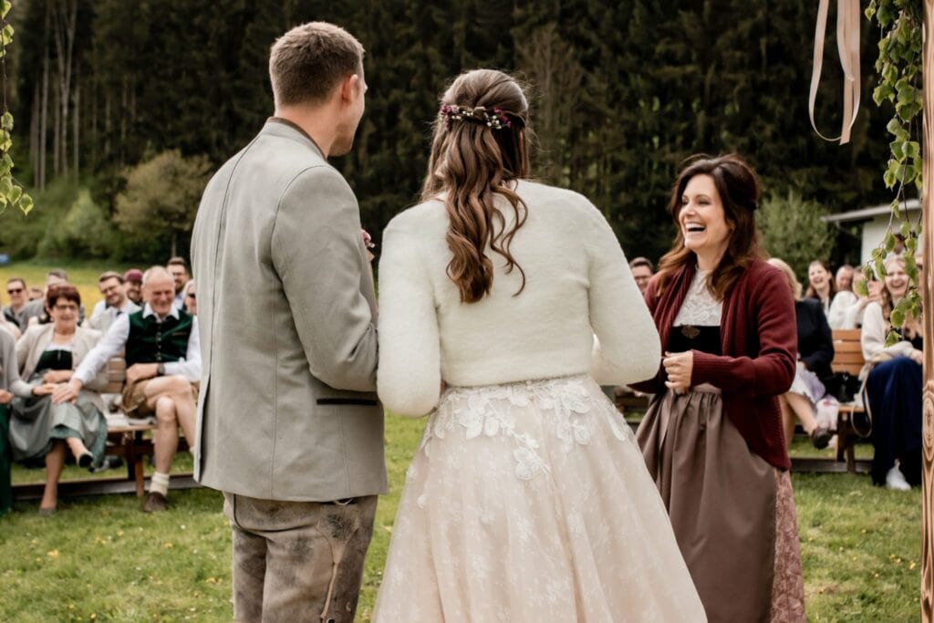 Hochzeitszeremonie im Freien mit einem Redner, Brautpaar und Gästen in einer natürlichen Umgebung, ideal für freie Redner bei Hochzeiten im Grünen.
