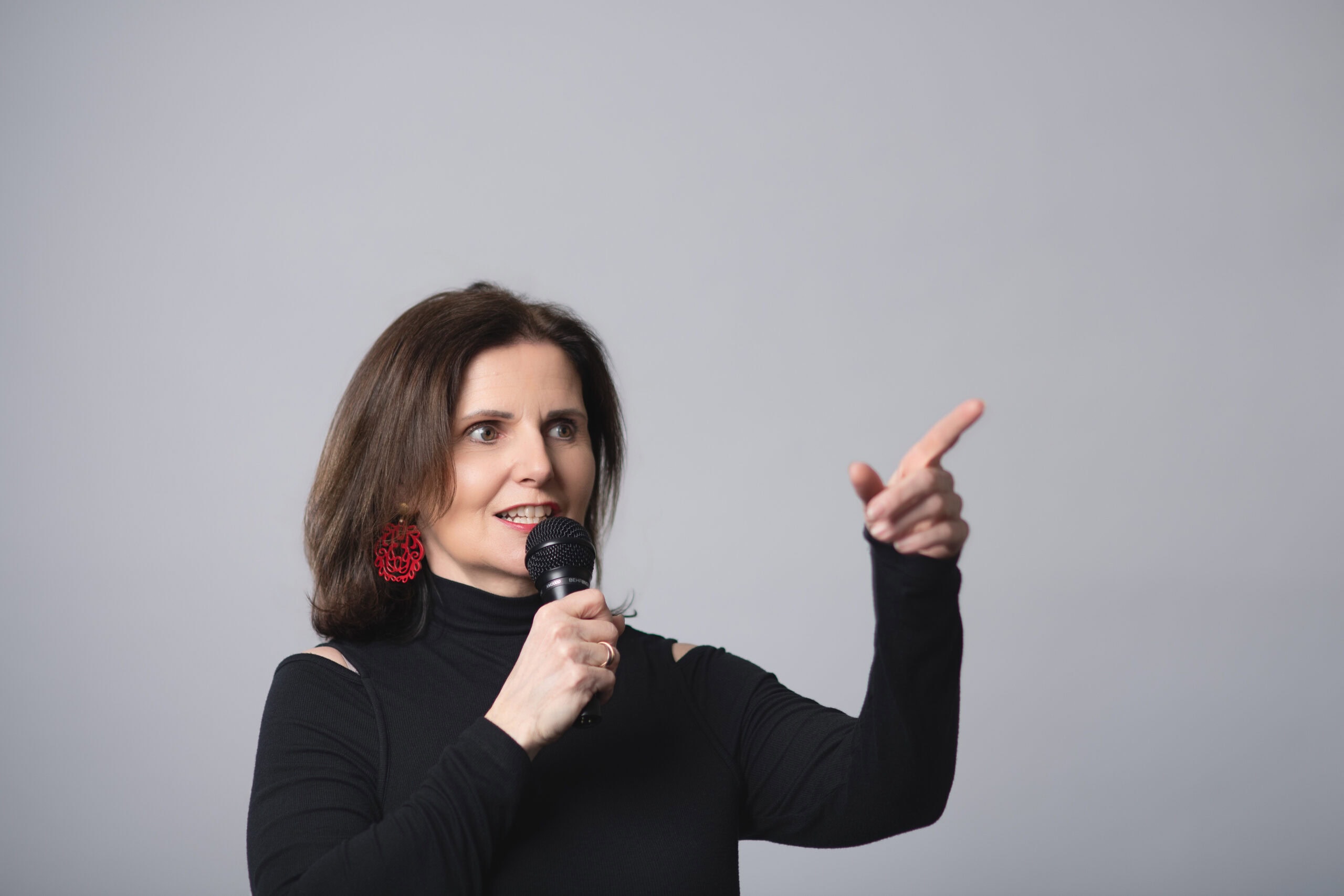 Freie Rednerin Maria Reingruber spricht in Mikrofon bei einer Veranstaltung, symbolisiert öffentliches Reden und Präsentation.