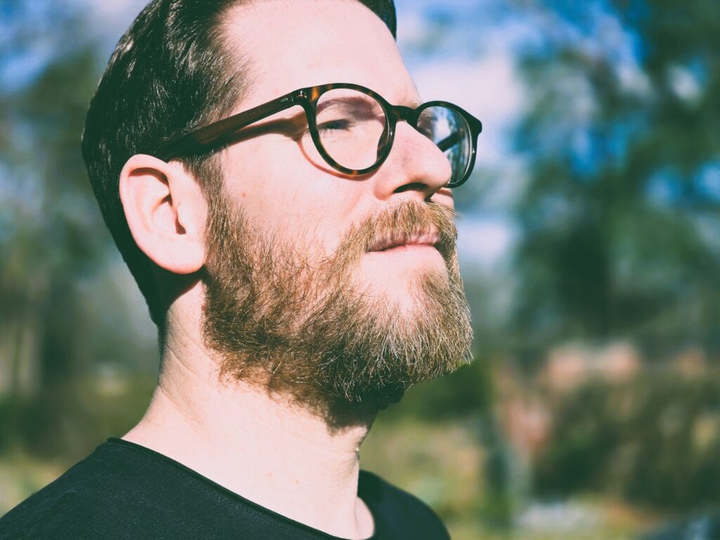 Ein Mann mit Brille und Bart, der im Freien steht, symbolisiert professionelle freie Redner für Veranstaltungen, Reden und Anlässe.