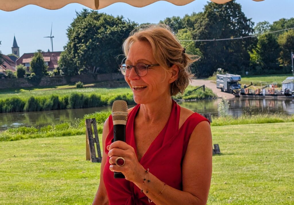 Freie Rednerin Mareike Bremer spricht ins Mikro bei einer Zeremonie draußen im Grünen