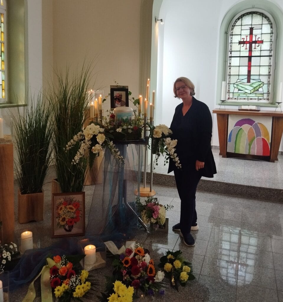 Frau bei Trauerfeier in Kirche mit Kerzen, Blumen und religiösen Symbolen, professionelle Redner für Beerdigungen und Trauerfeiern in Deutschland.