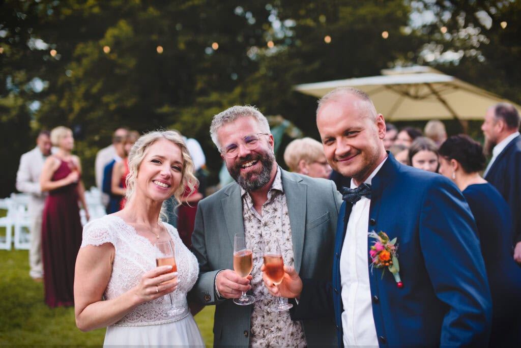 Freie Redner bei einer Hochzeitsfeier im Garten, lachende Gäste mit Sektgläsern, festliche Atmosphäre, outdoor Event, professionelle Redner für Hochzeiten.