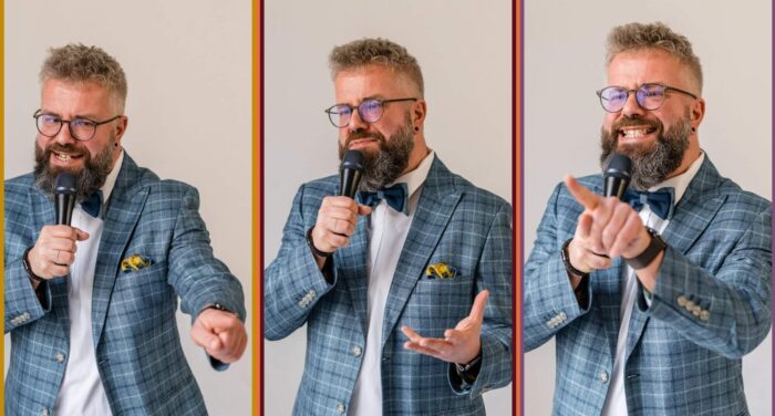 Freier Redner bei einer Rede, trägt Brille, graues Haar, blauer Anzug mit Krawatte, spricht in Mikrofon, vor neutralem Hintergrund.
